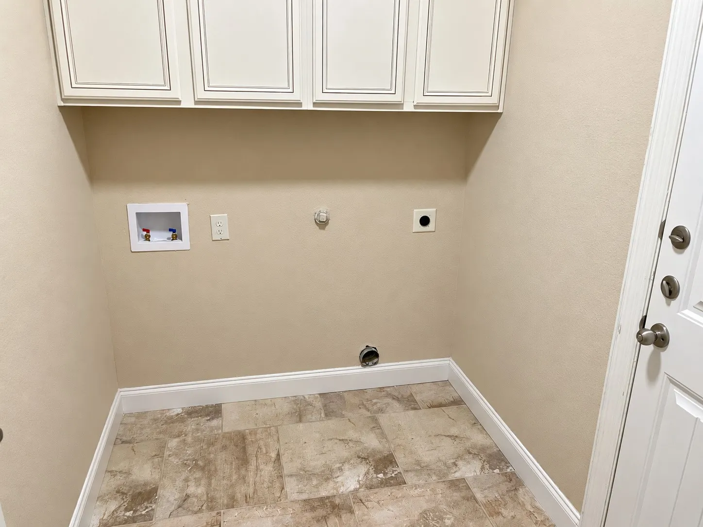 Utility area featuring upper cabinetry, tile flooring, and a paneled door