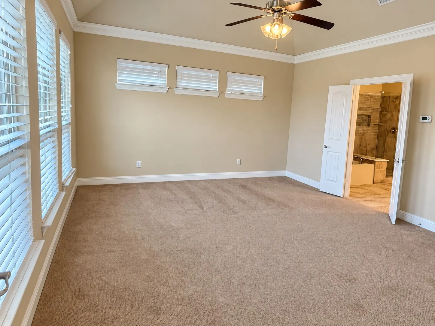 Vaulted ceiling with a ceiling fan, crown molding, multiple windows with blinds, and carpet flooring