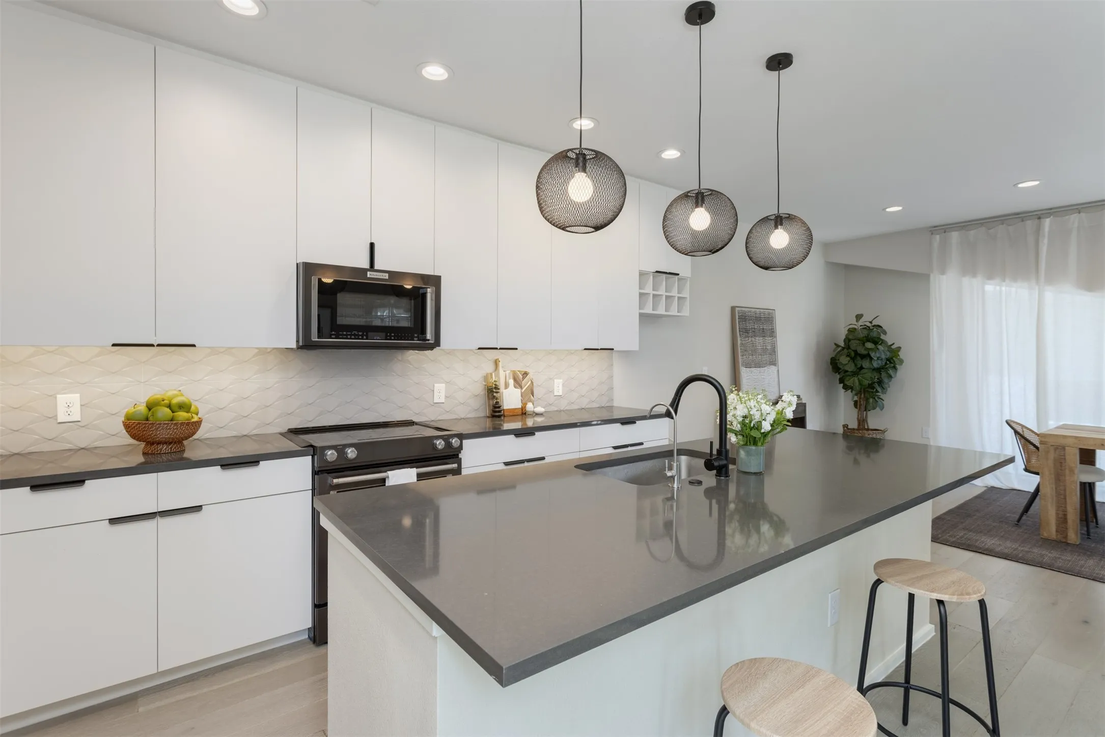Kitchen with light wood finished floors, a kitchen bar, white cabinets, and stainless steel appliances