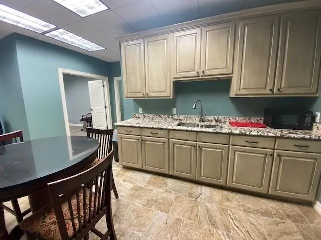 Kitchen featuring light stone counters, sink, and a drop ceiling