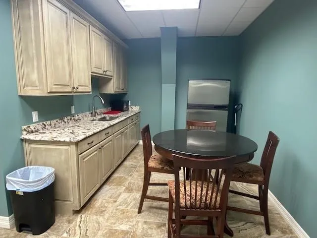 Kitchen featuring stainless steel fridge, light stone counters, and sink