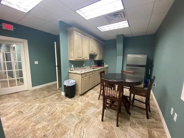 Kitchen with a paneled ceiling, light stone counters, and sink