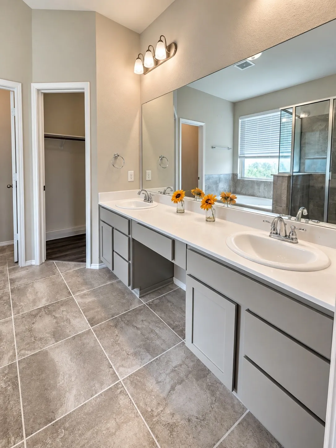Spacious bathroom featuring a dual vanity with ample storage, large wall mirror, and tiled flooring