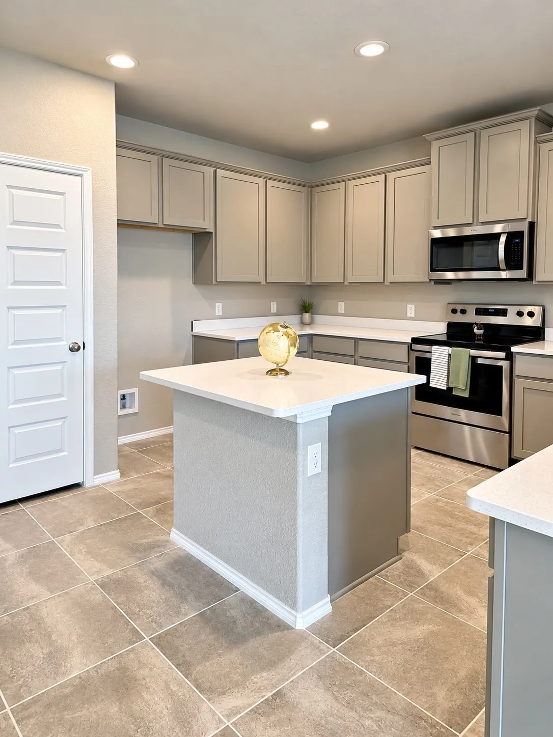 Kitchen featuring extensive cabinetry, a central island with a white countertop, stainless steel appliances, recessed lighting, and large format tile flooring