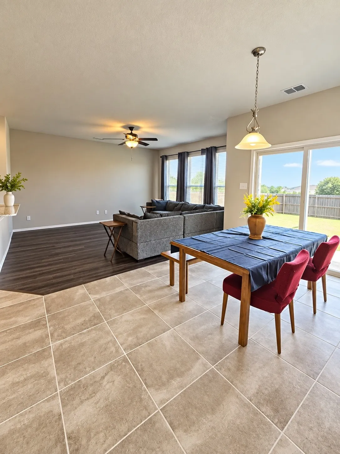 Spacious living area featuring wood-finish flooring, a ceiling fan, and abundant natural light from multiple windows
