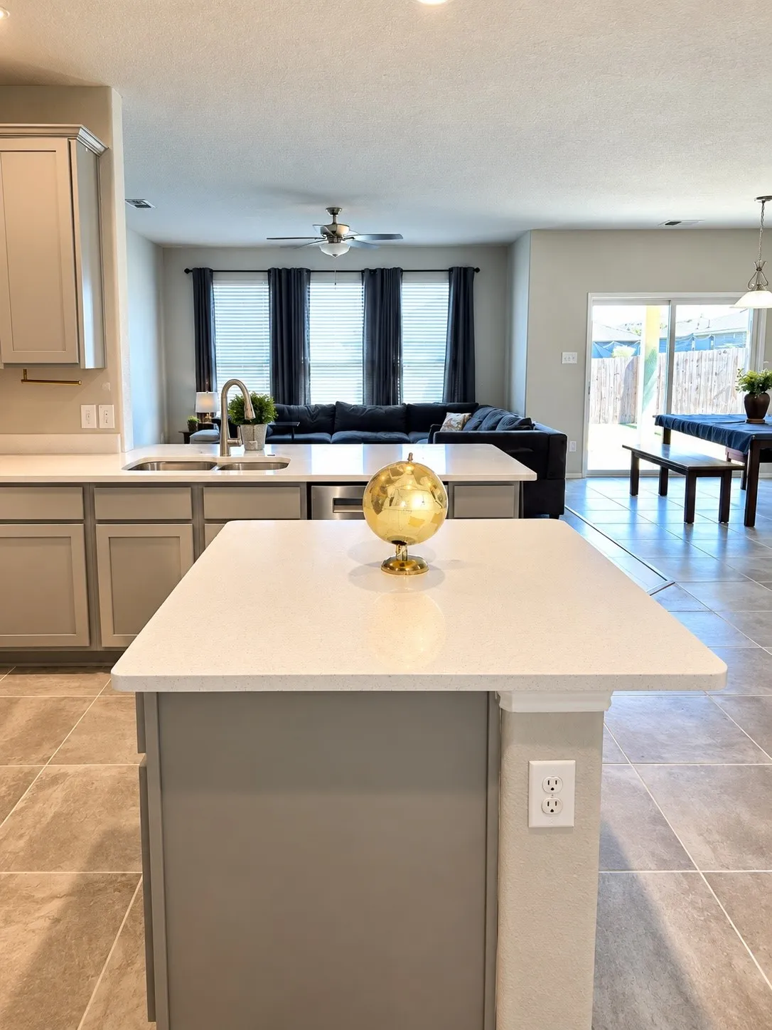 Kitchen island with light-toned countertop, gray cabinetry, and tile flooring