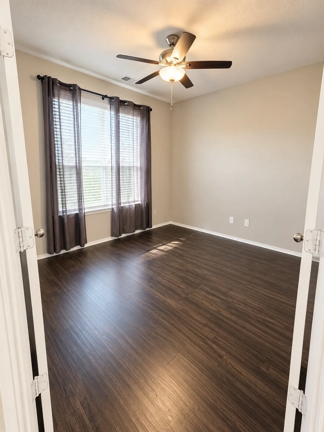 Wood-finish flooring with a ceiling fan and overhead light fixture