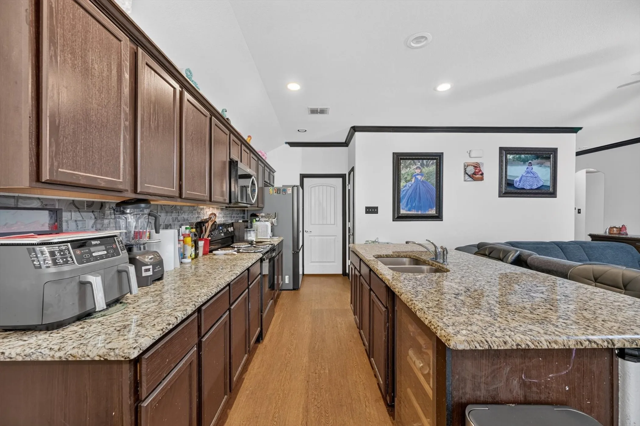 Expansive kitchen featuring wood-finish cabinetry, speckled countertops, a tile backsplash, and recessed lighting