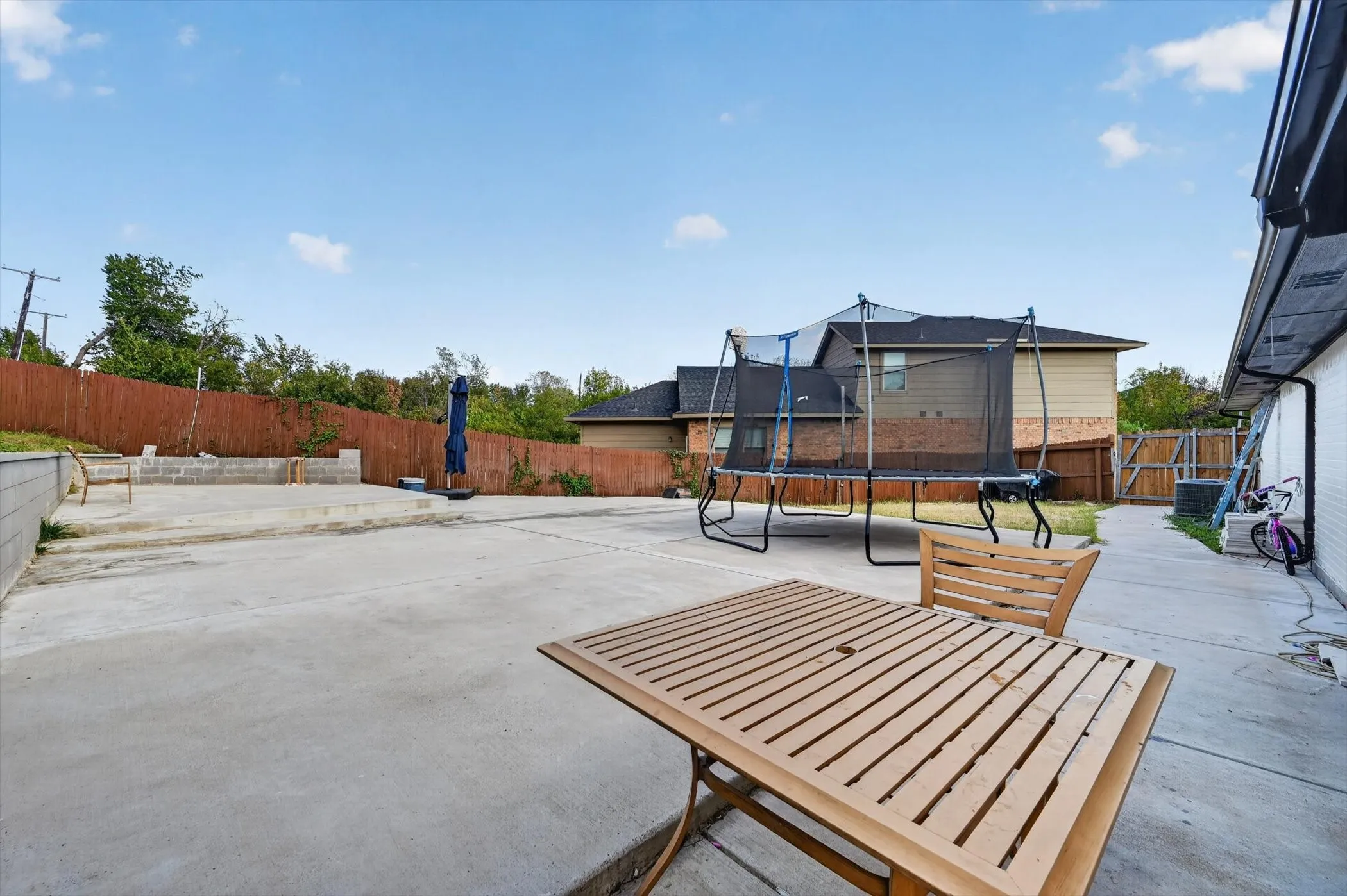 Expansive concrete patio with a privacy fence and a dedicated raised garden bed