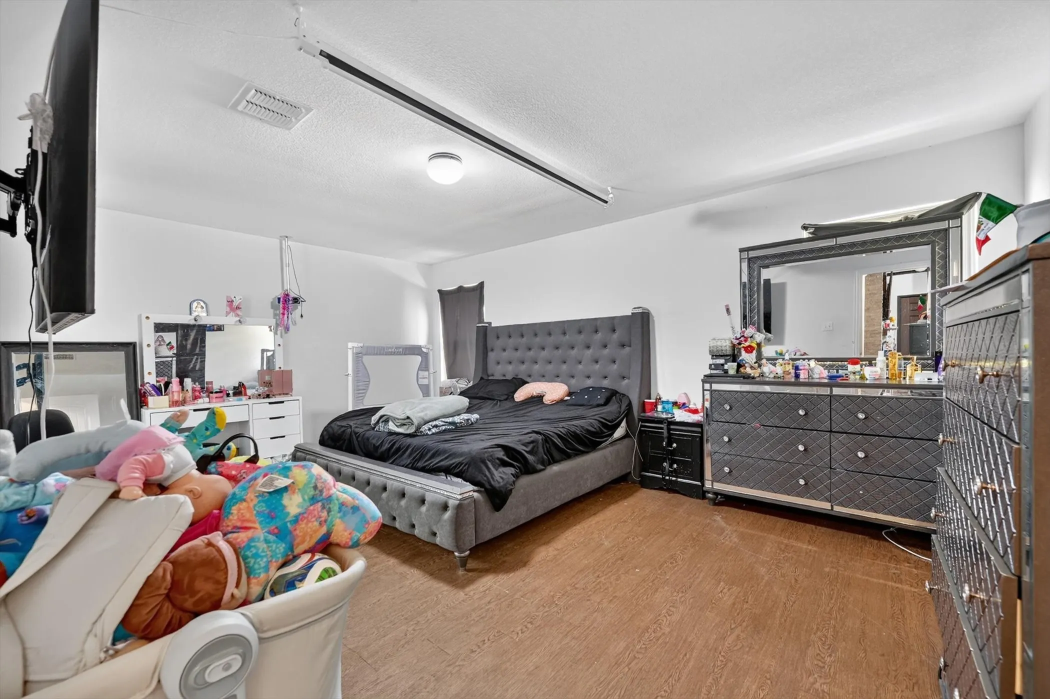 Wood-finish flooring with white walls and a ceiling-mounted light fixture