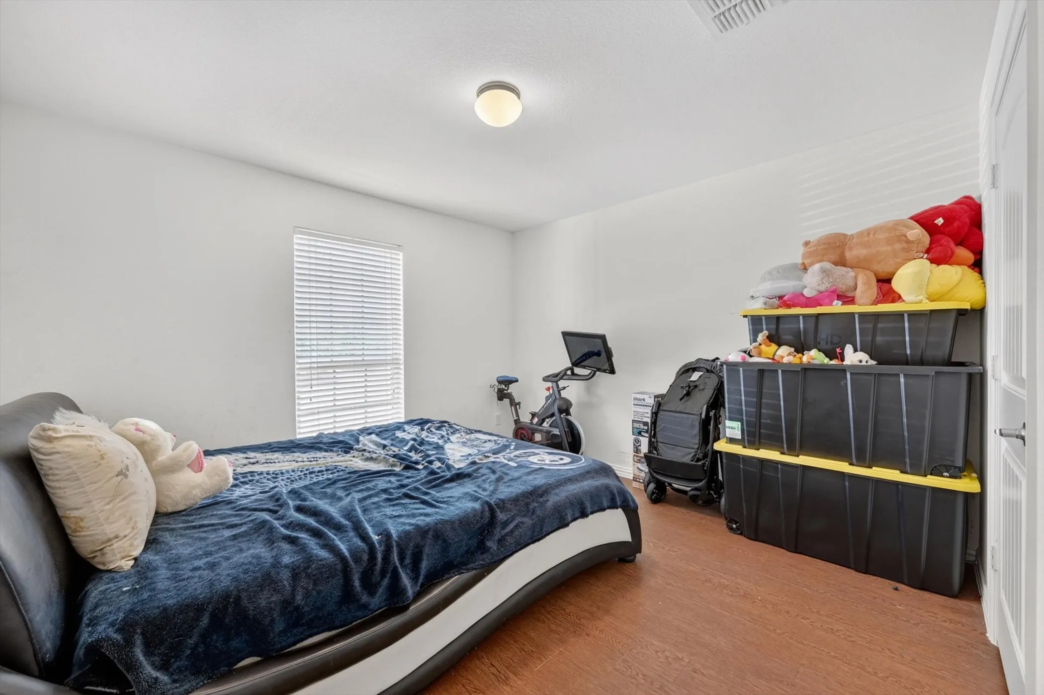 Wood-finish flooring, white walls, and a window with blinds