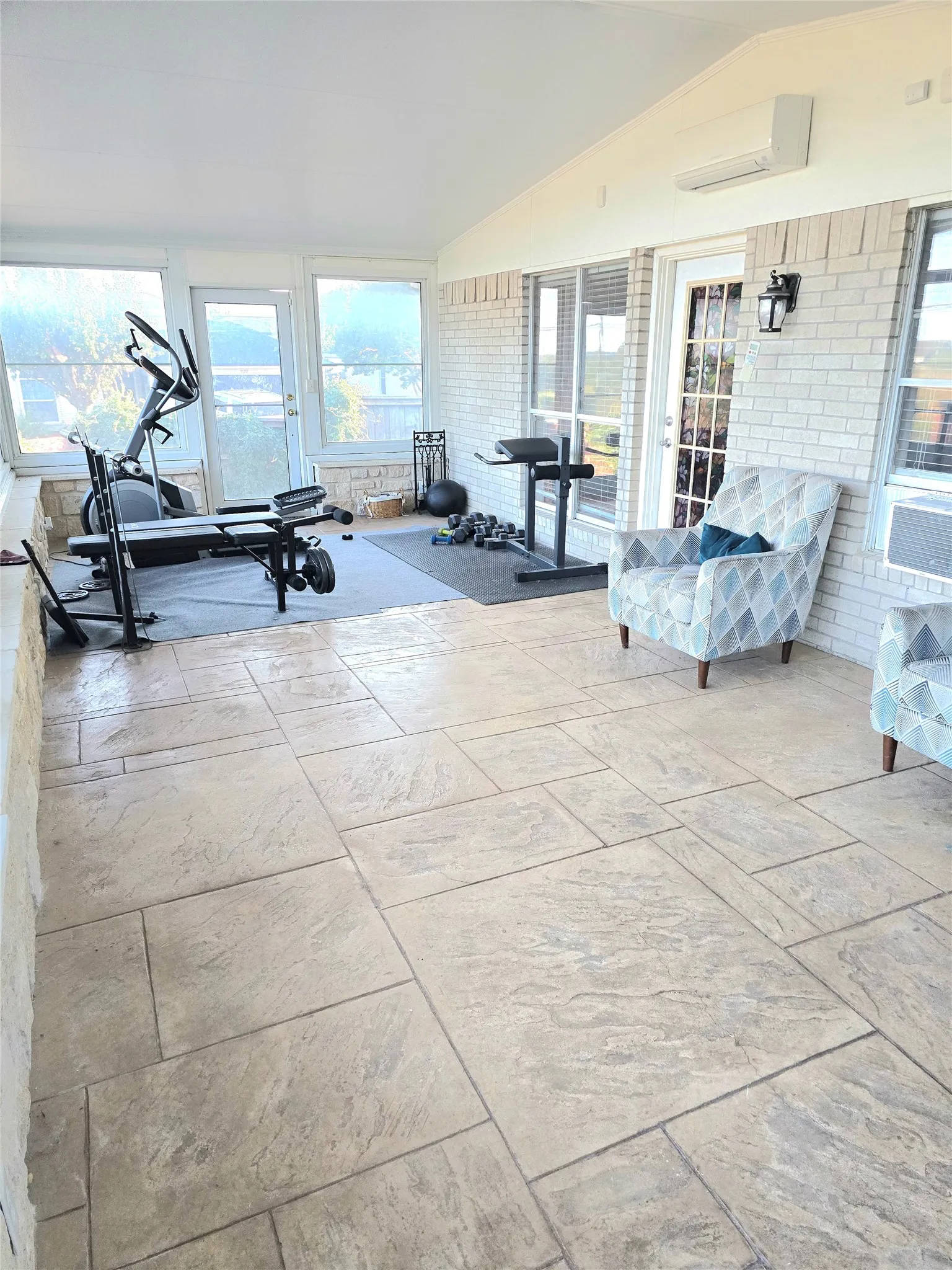 Spacious room featuring large format tile flooring and white painted brick accents