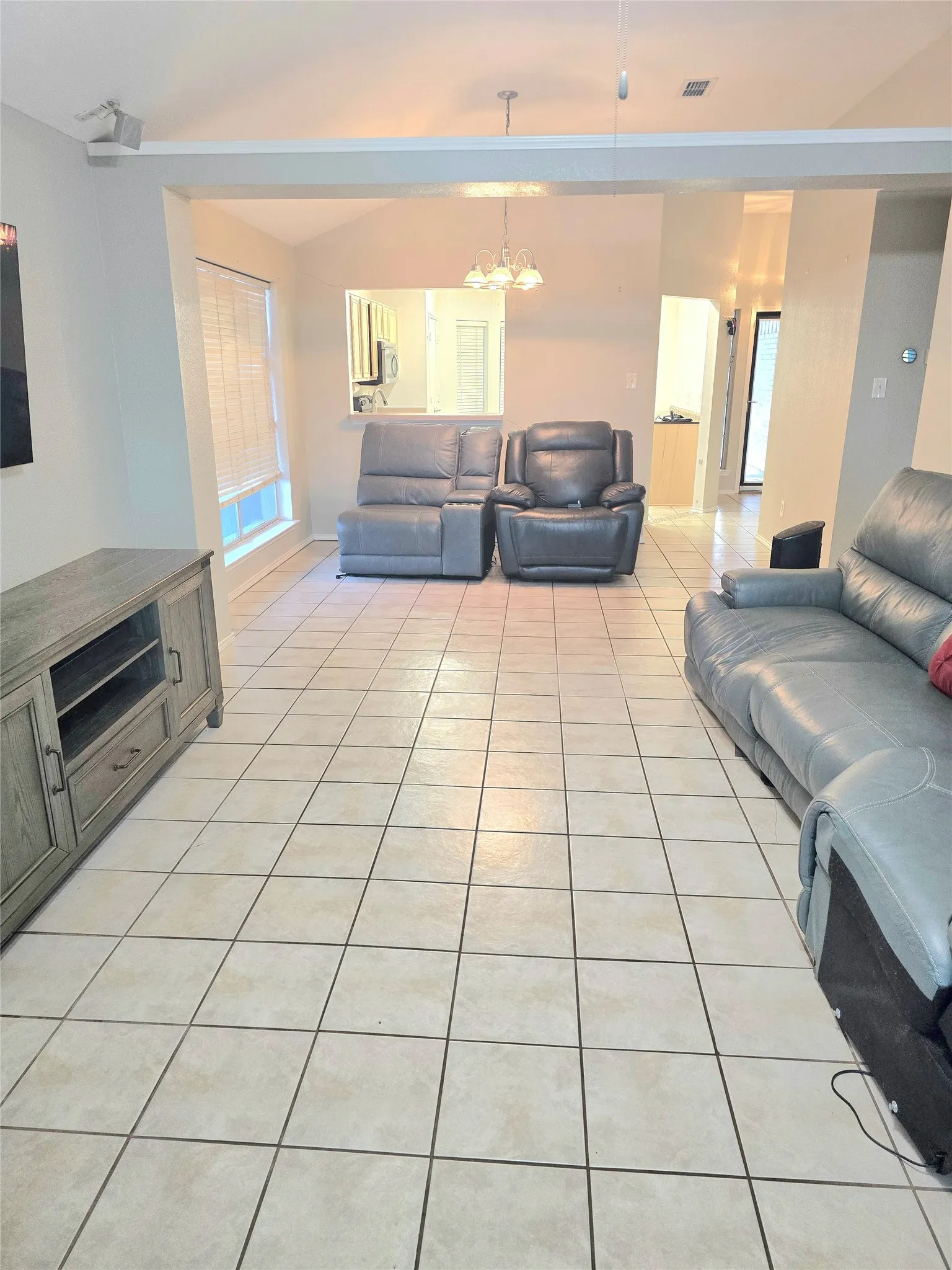 Vaulted ceiling, square tile flooring, window with blinds, recessed lighting, and a pass-through opening to another room