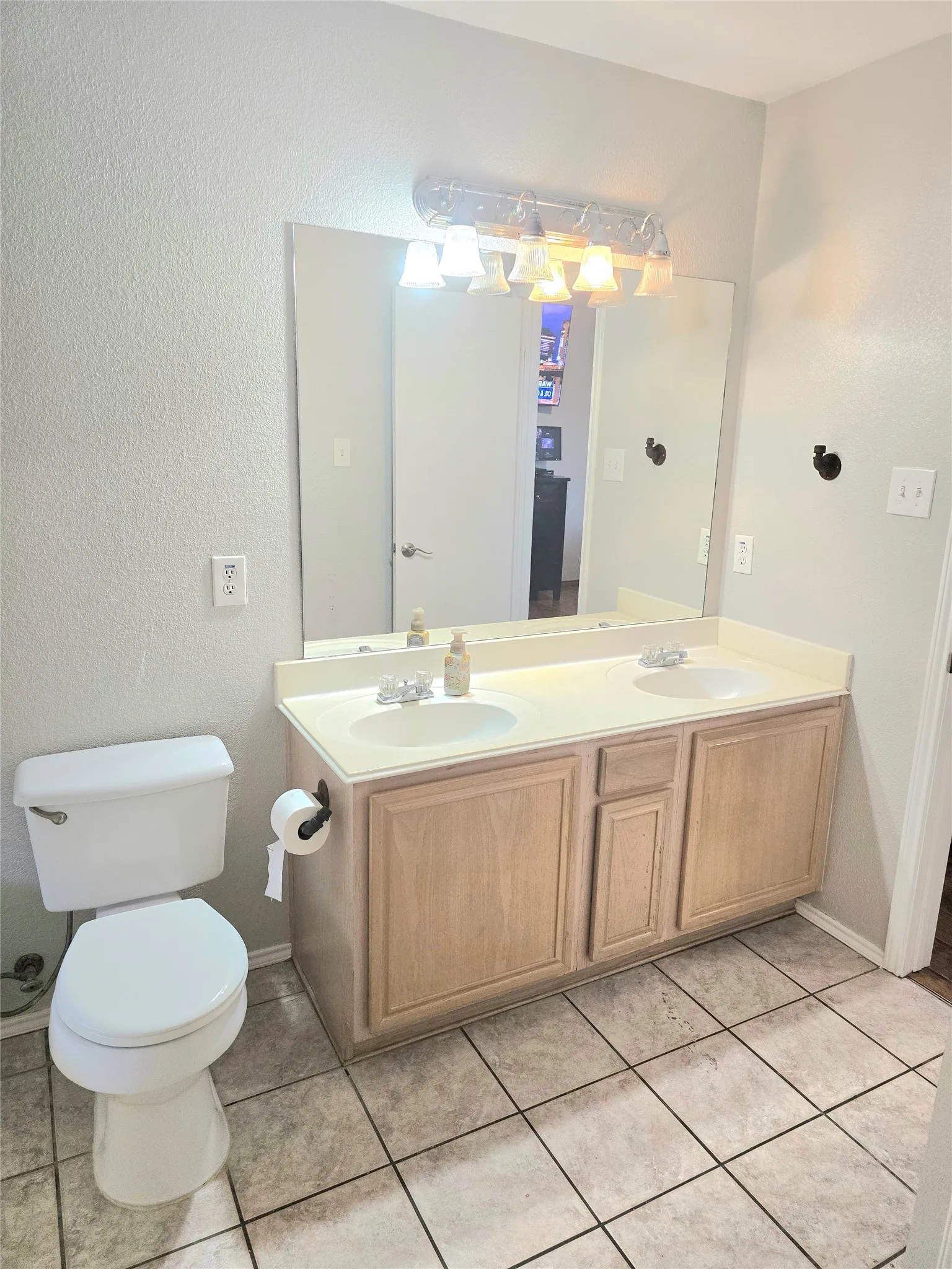 Dual vanity with integrated sinks, light-toned cabinetry, and a large wall-mounted mirror