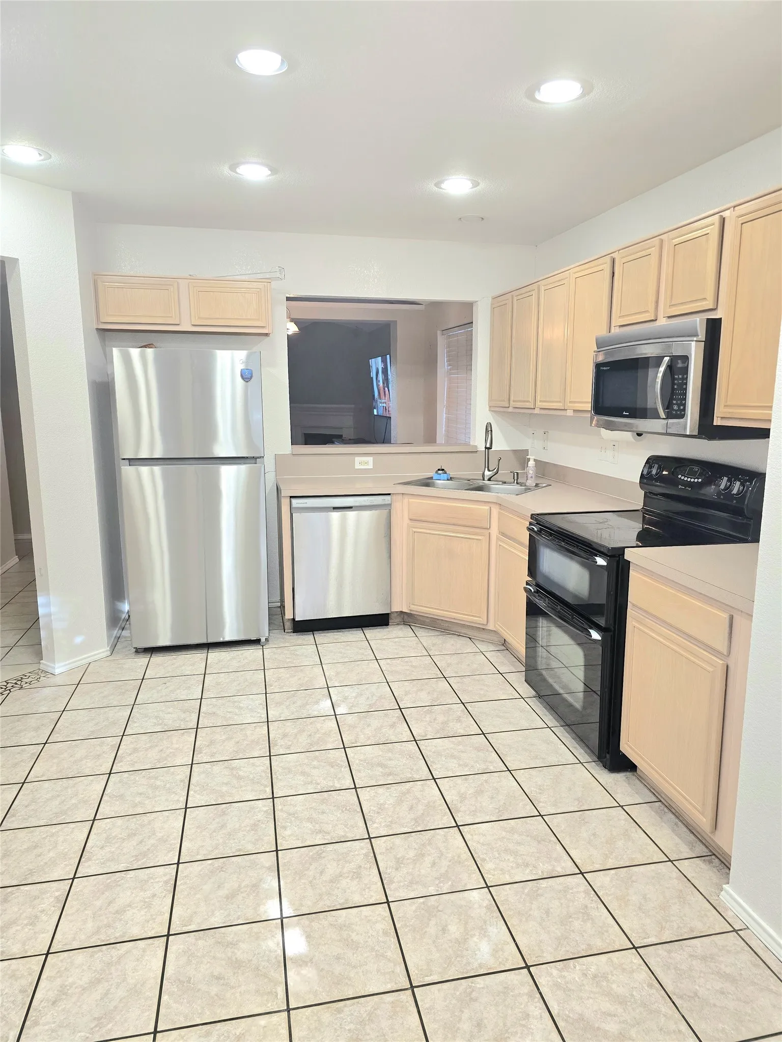 Kitchen featuring tile flooring, stainless steel appliances, recessed lighting, double wall oven, and wood cabinetry