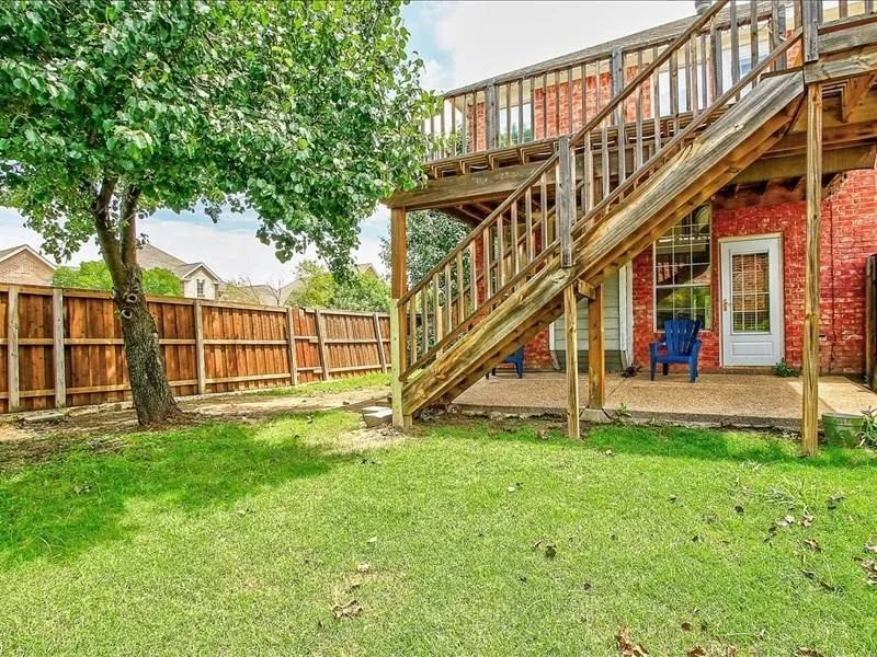 Expansive backyard featuring a manicured lawn, wood privacy fence, and mature tree