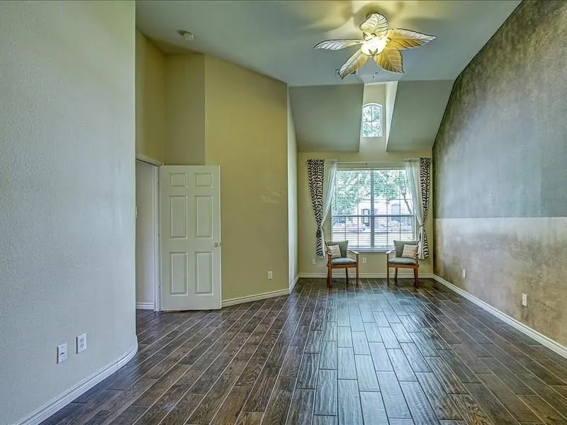 Vaulted ceilings, wood-finish flooring, and a decorative ceiling fan with lighting