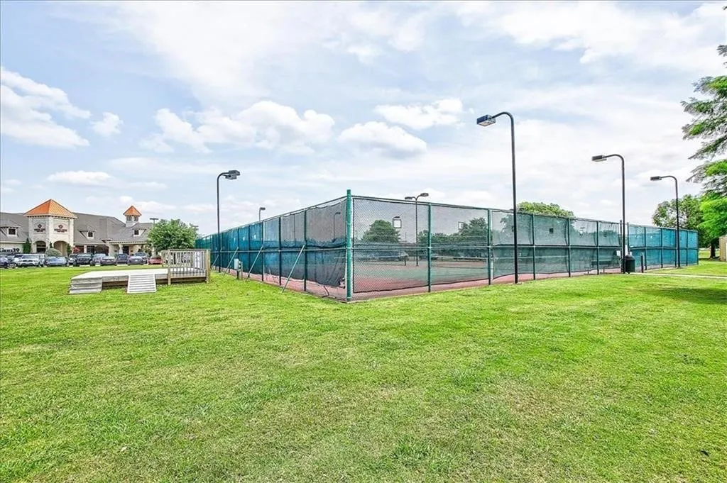 Tennis court facility with chain-link fencing, court lighting, and a paved playing surface