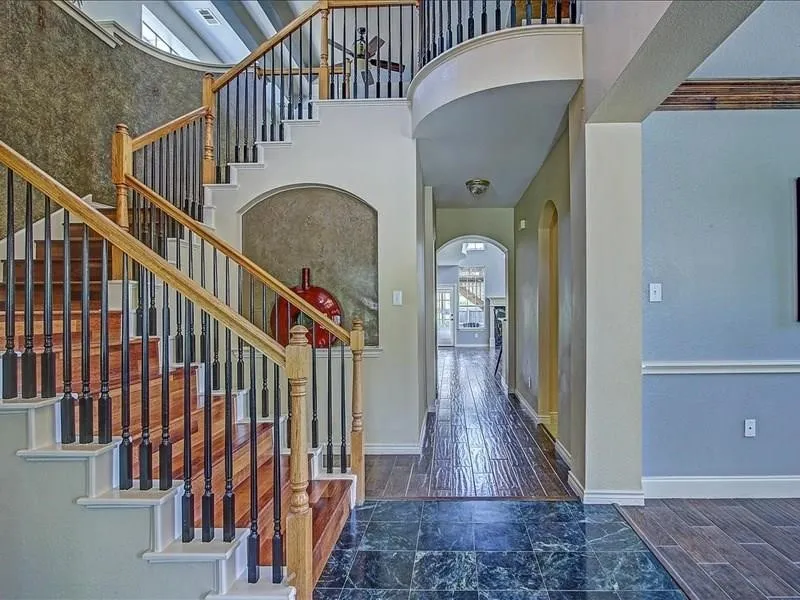 Grand entryway featuring a two-story staircase with wood treads and wrought iron spindles