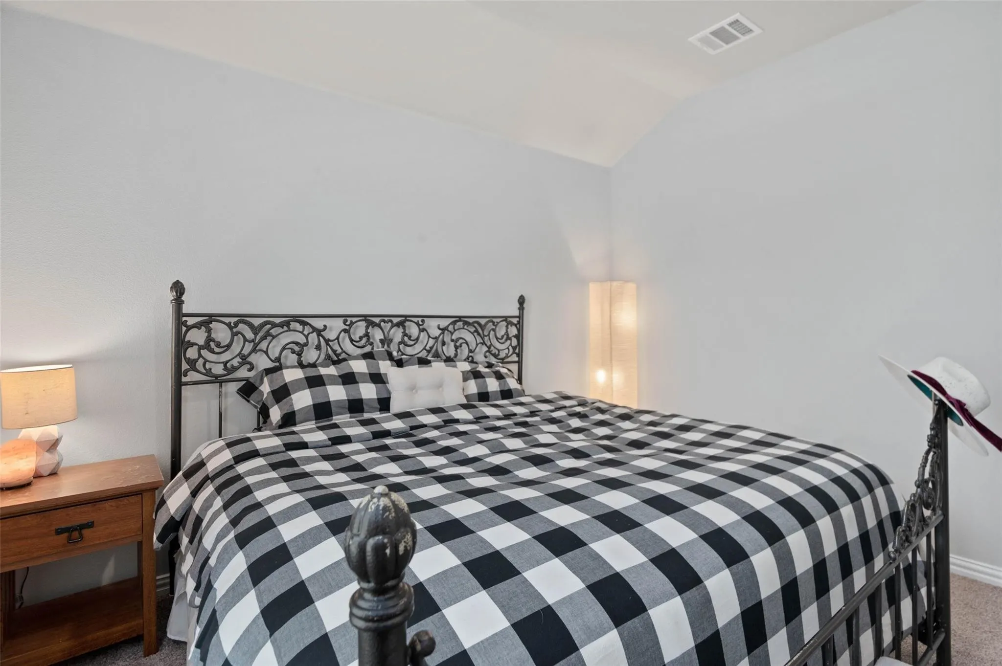 Vaulted ceiling with textured walls and carpet flooring