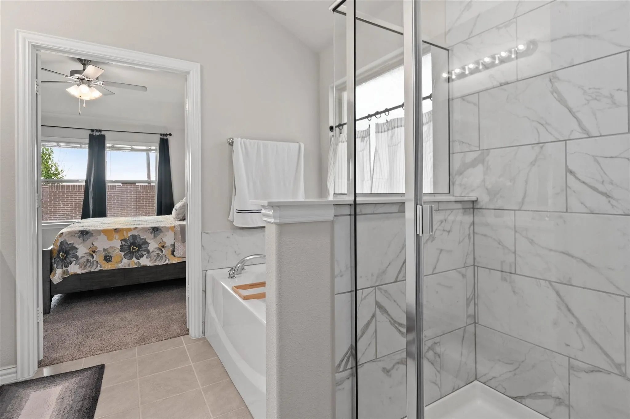 Tiled shower with glass enclosure, separate soaking tub, and tile flooring