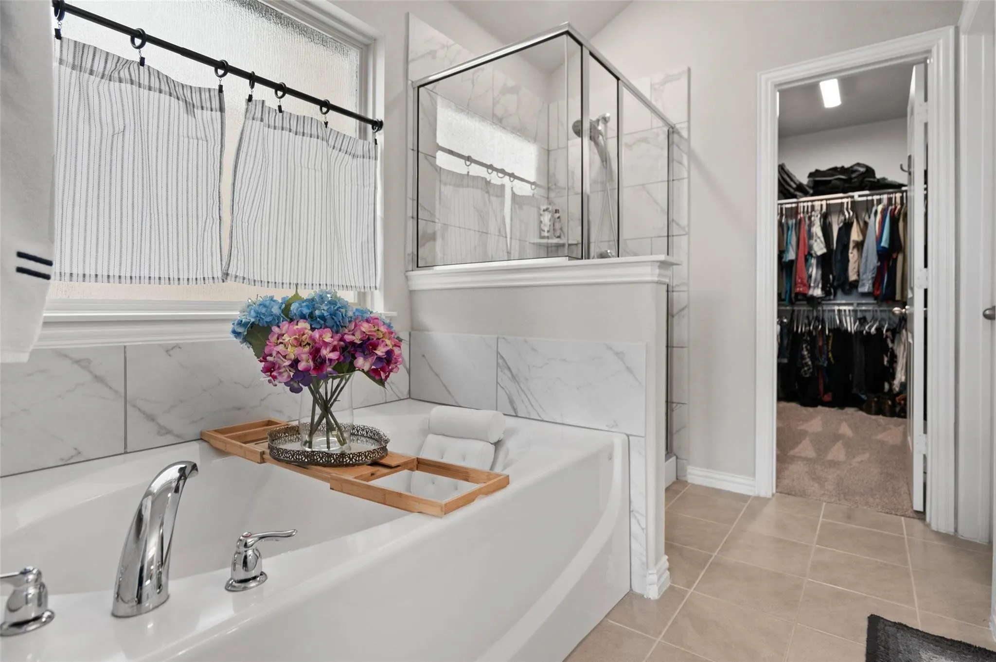 Soaking tub with chrome fixtures, tiled shower enclosure, white wall tile, and light-toned floor tiles