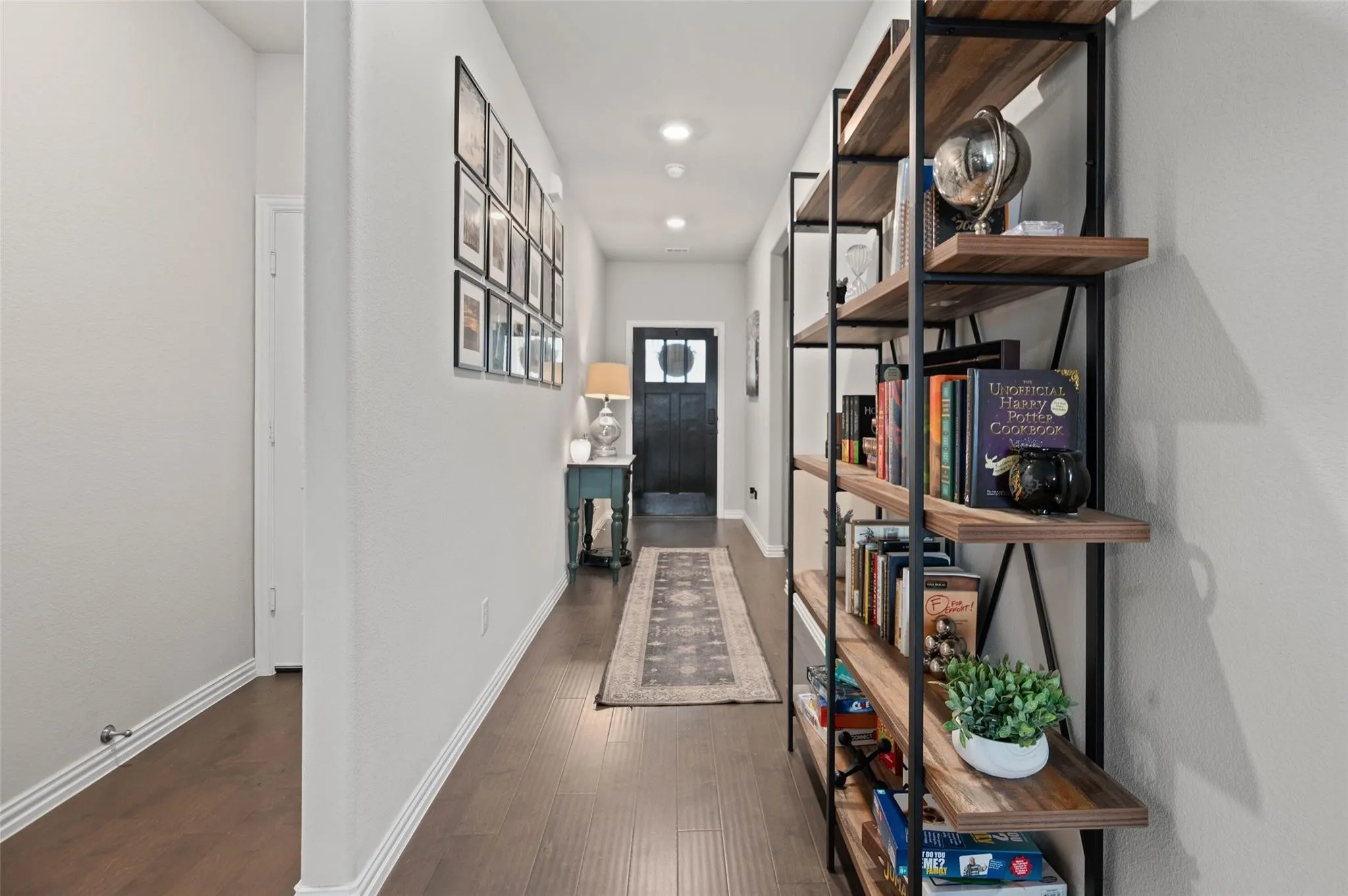 Hallway featuring wood-finish flooring, recessed lighting, and a built-in shelving unit with wood-finish shelves and a dark metal frame
