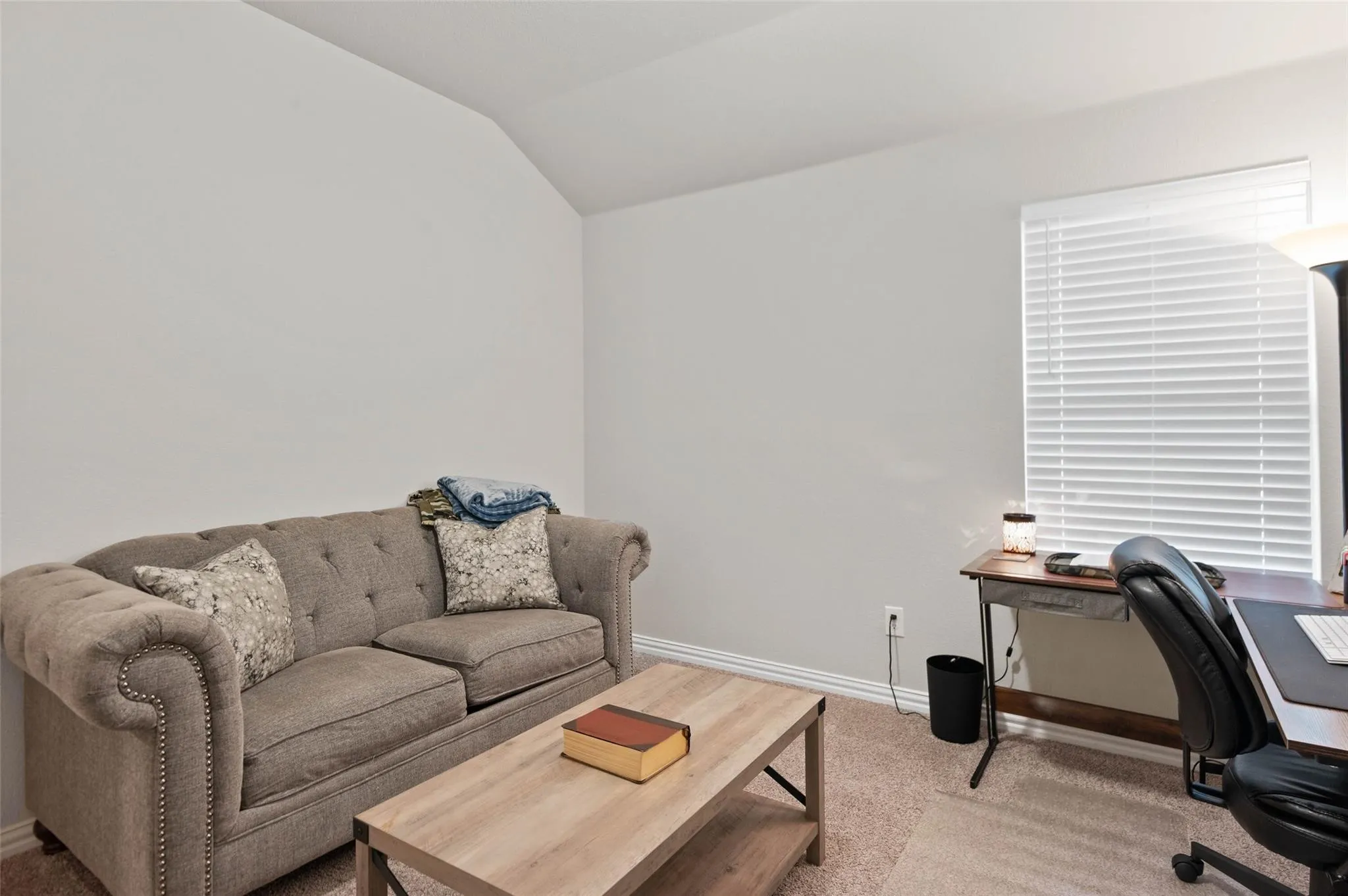 Vaulted ceiling with neutral wall tones and window with blinds