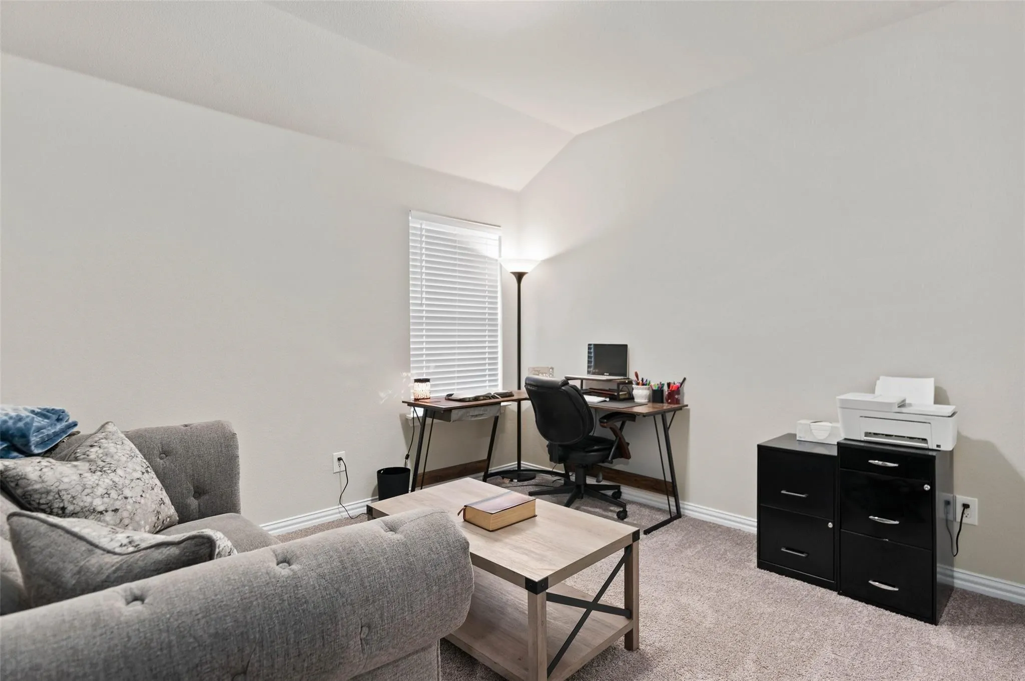 Carpeted room with a vaulted ceiling and neutral wall tones