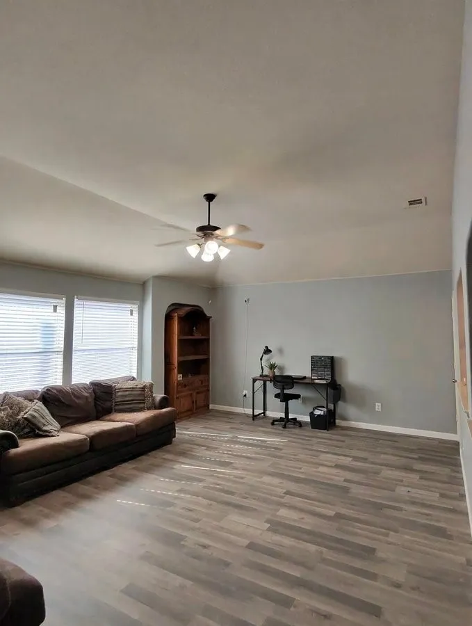 Vaulted ceiling with a ceiling fan, wood-finish flooring, and multiple windows