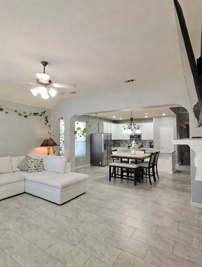 Vaulted ceiling, ceiling fan, tile flooring throughout, recessed lighting, and a kitchen with white cabinetry