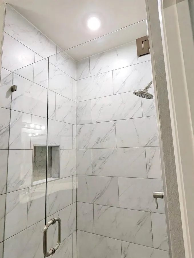 Walk-in shower with full-height subway tile, glass enclosure, recessed lighting, and a built-in shower niche with hex tile