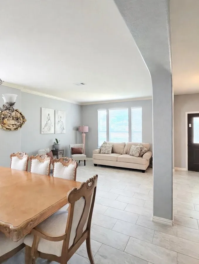 Expansive tiled flooring throughout, complemented by light gray wall tones and white crown molding
