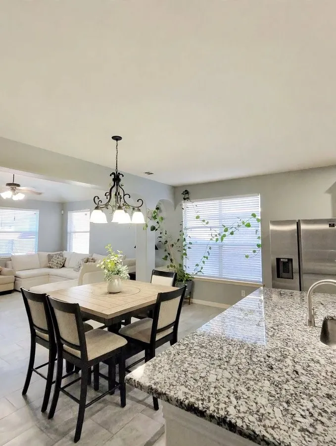 Granite-finish countertop, stainless steel refrigerator, white window blinds, and recessed lighting