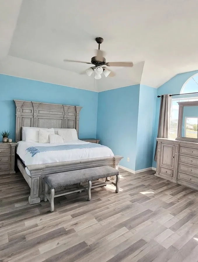Wood-finish flooring, vaulted ceiling, ceiling fan with light fixture, and arched window