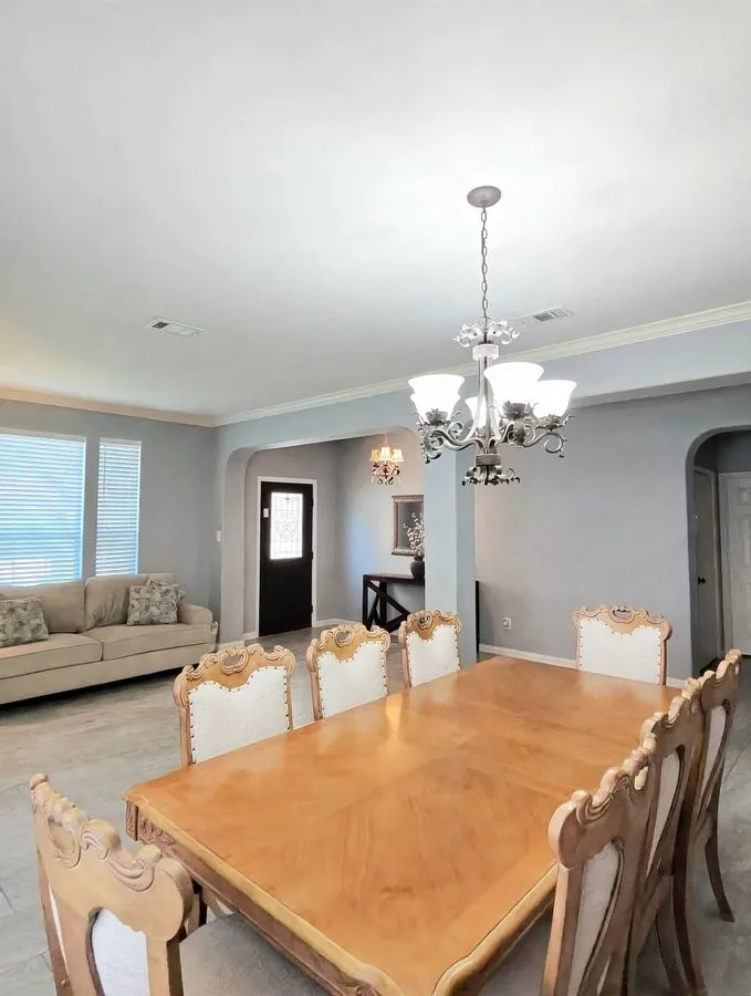 Tray ceiling with a decorative chandelier, crown molding, and tiled flooring