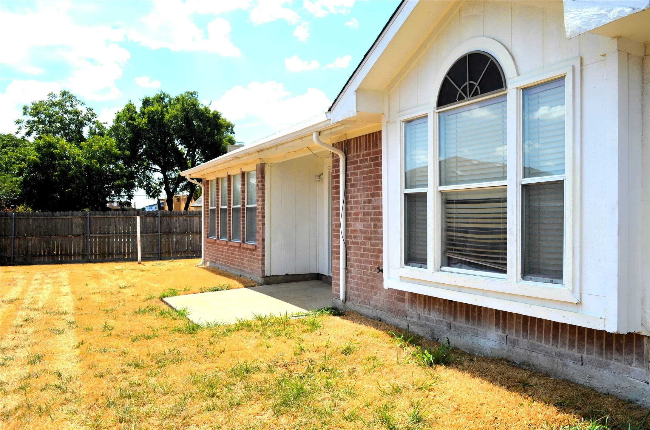 Brick exterior with white trim, featuring a bay window with an arched transom