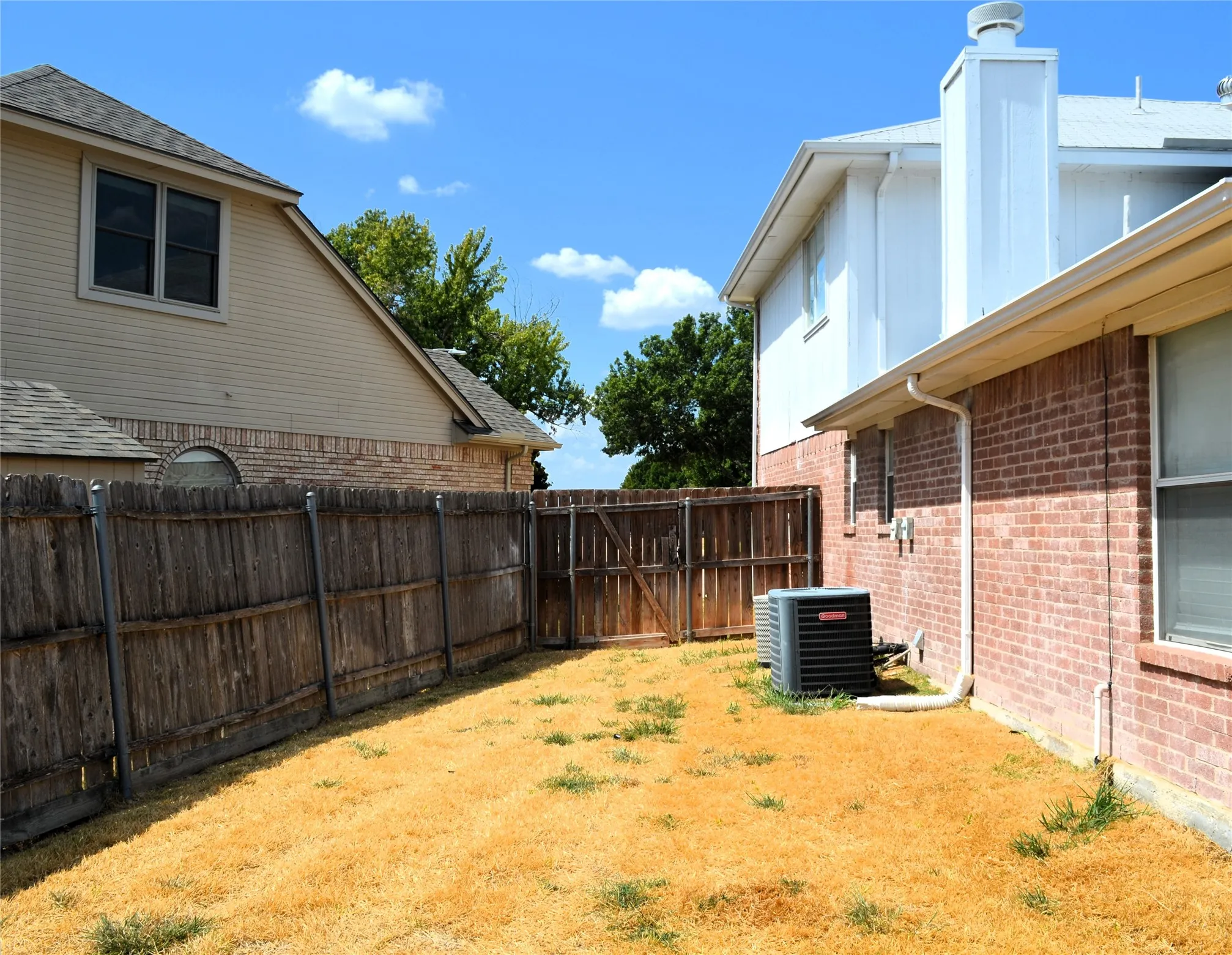 Brick exterior with white trim, wood privacy fence, and an outdoor HVAC unit