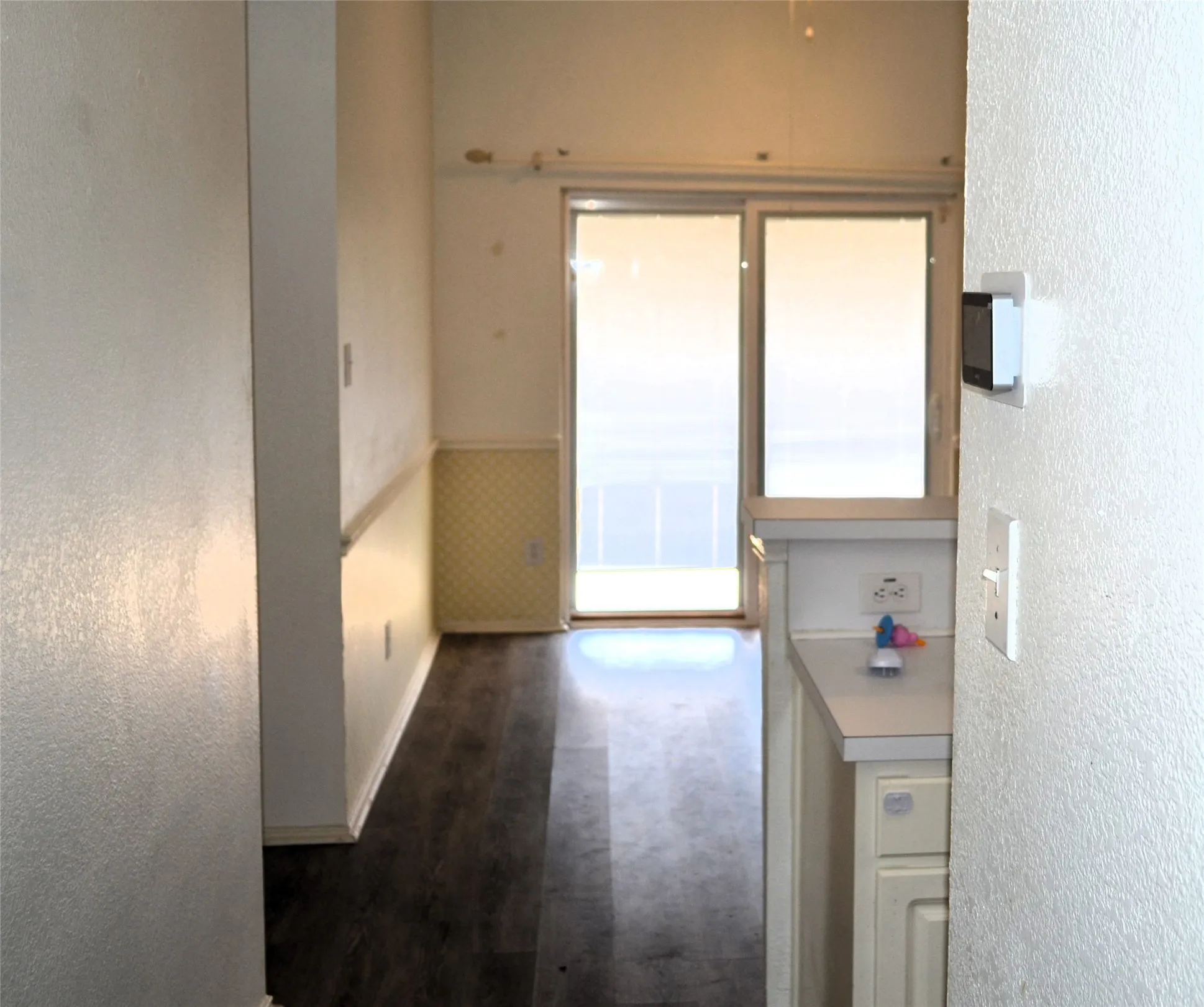 Sliding glass door, wood-finish flooring, half-wall wainscoting, and white cabinetry