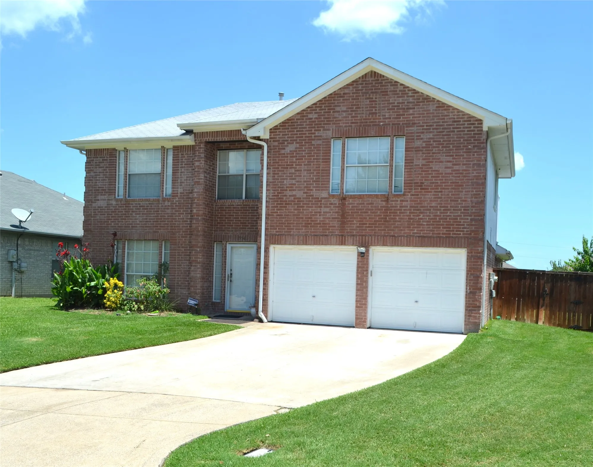 Brick exterior with a two-car garage, white garage doors, and a concrete driveway