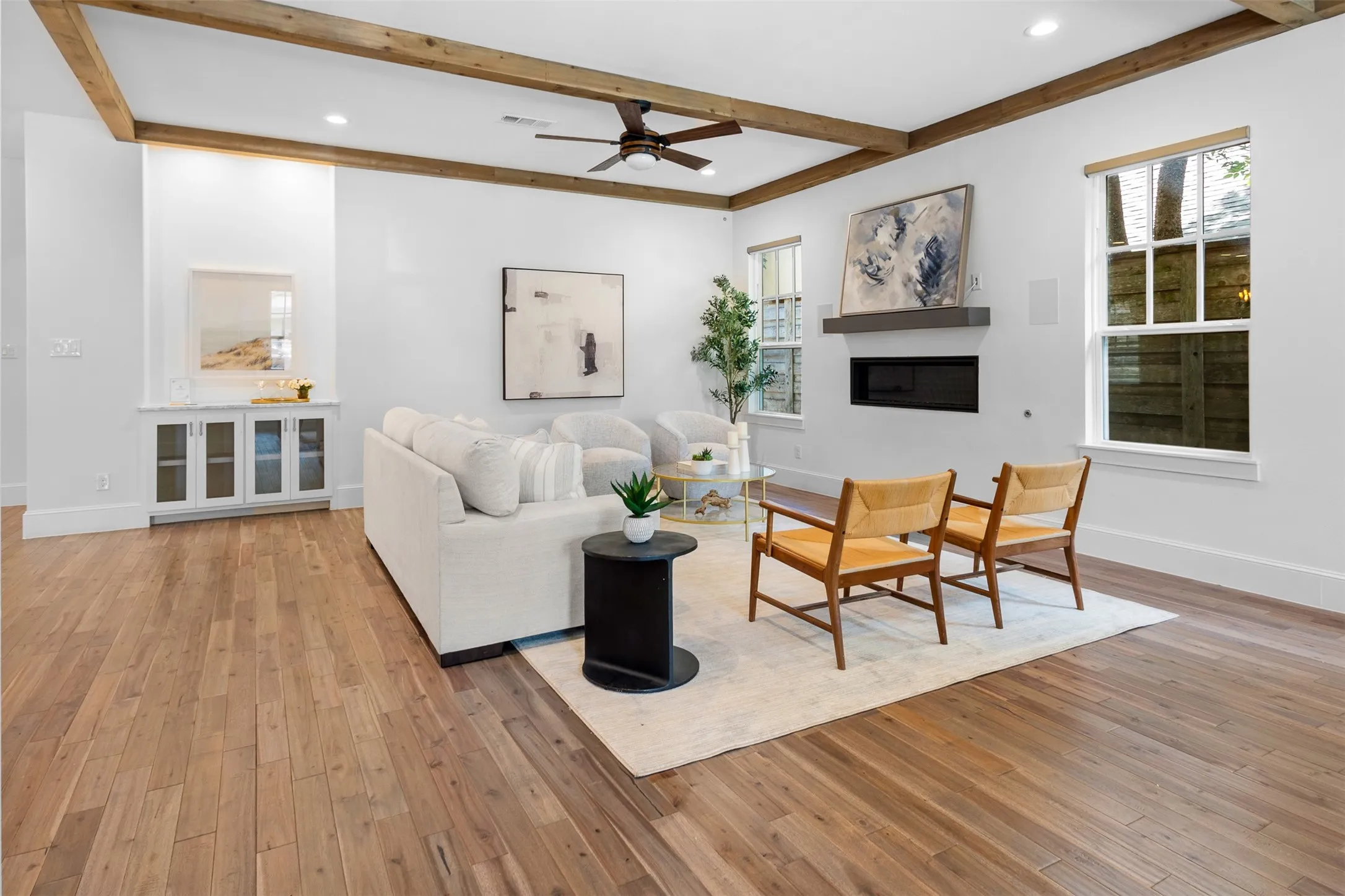 Exposed wood beams, wood-finish flooring, recessed lighting, built-in cabinetry with glass doors, and a fixed fireplace with a mantel