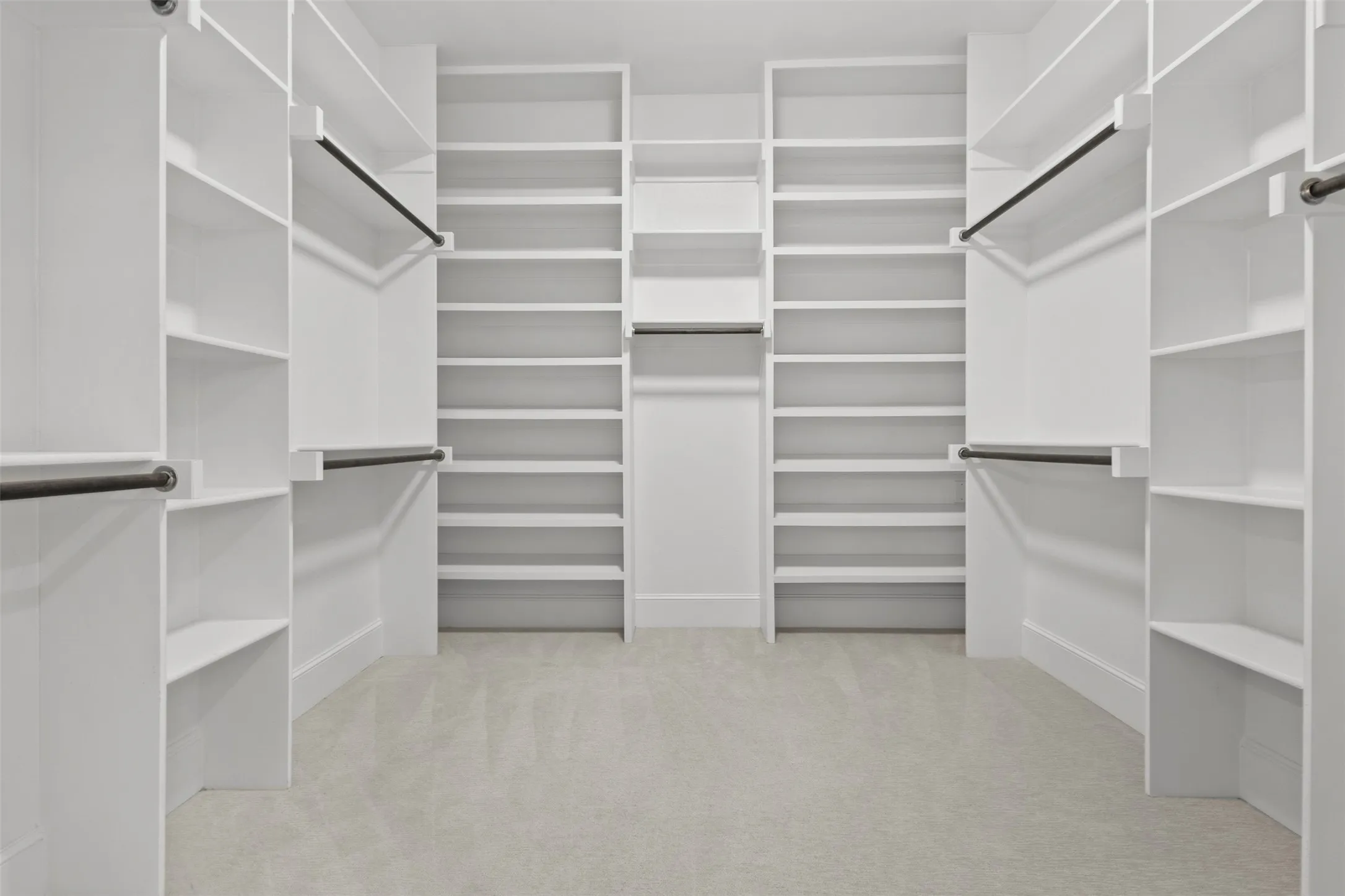 Built-in shelving with multiple hanging rods, extensive custom storage, and light-colored carpeting
