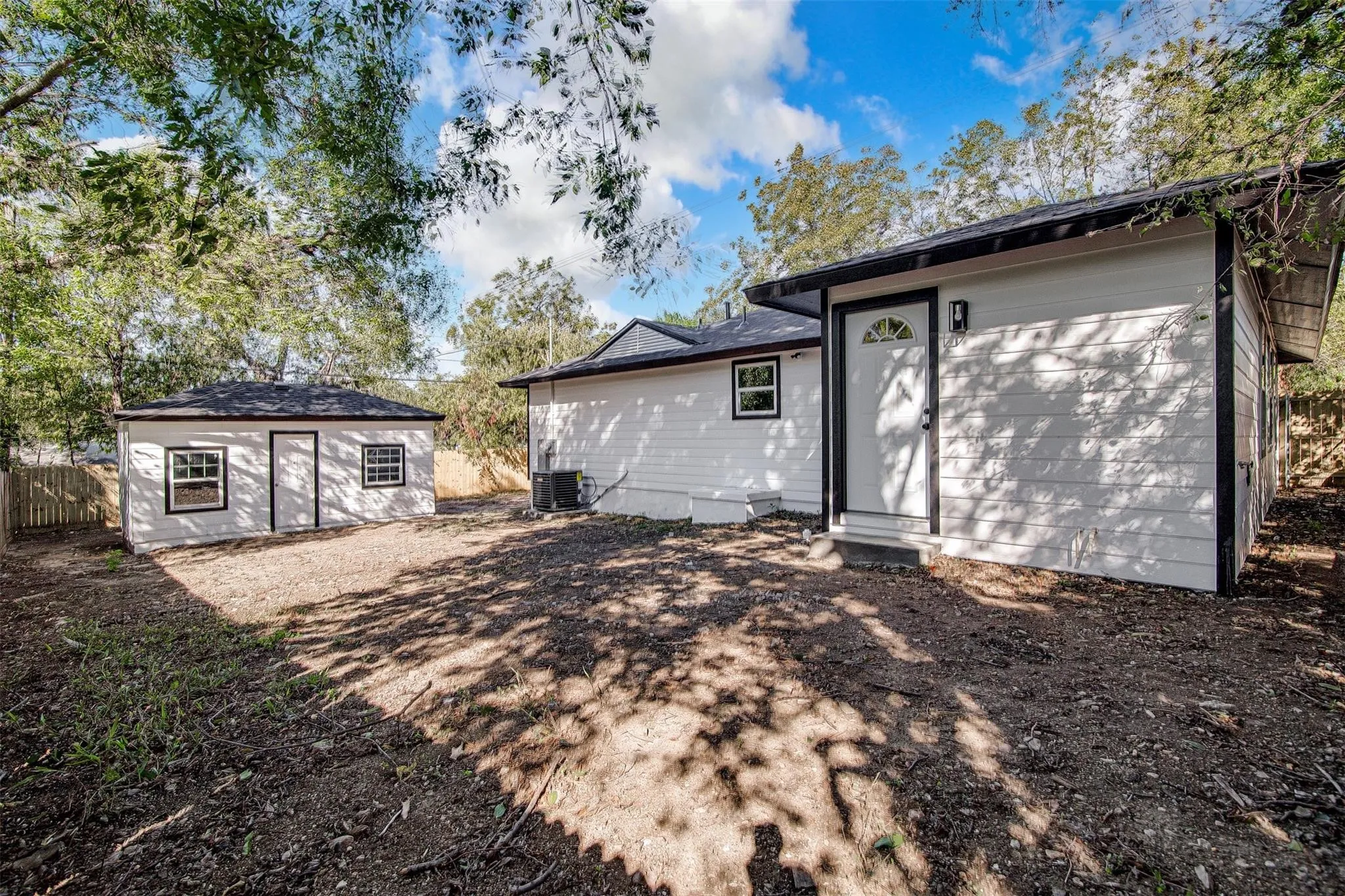 Exterior featuring white siding, black trim, and a separate auxiliary structure