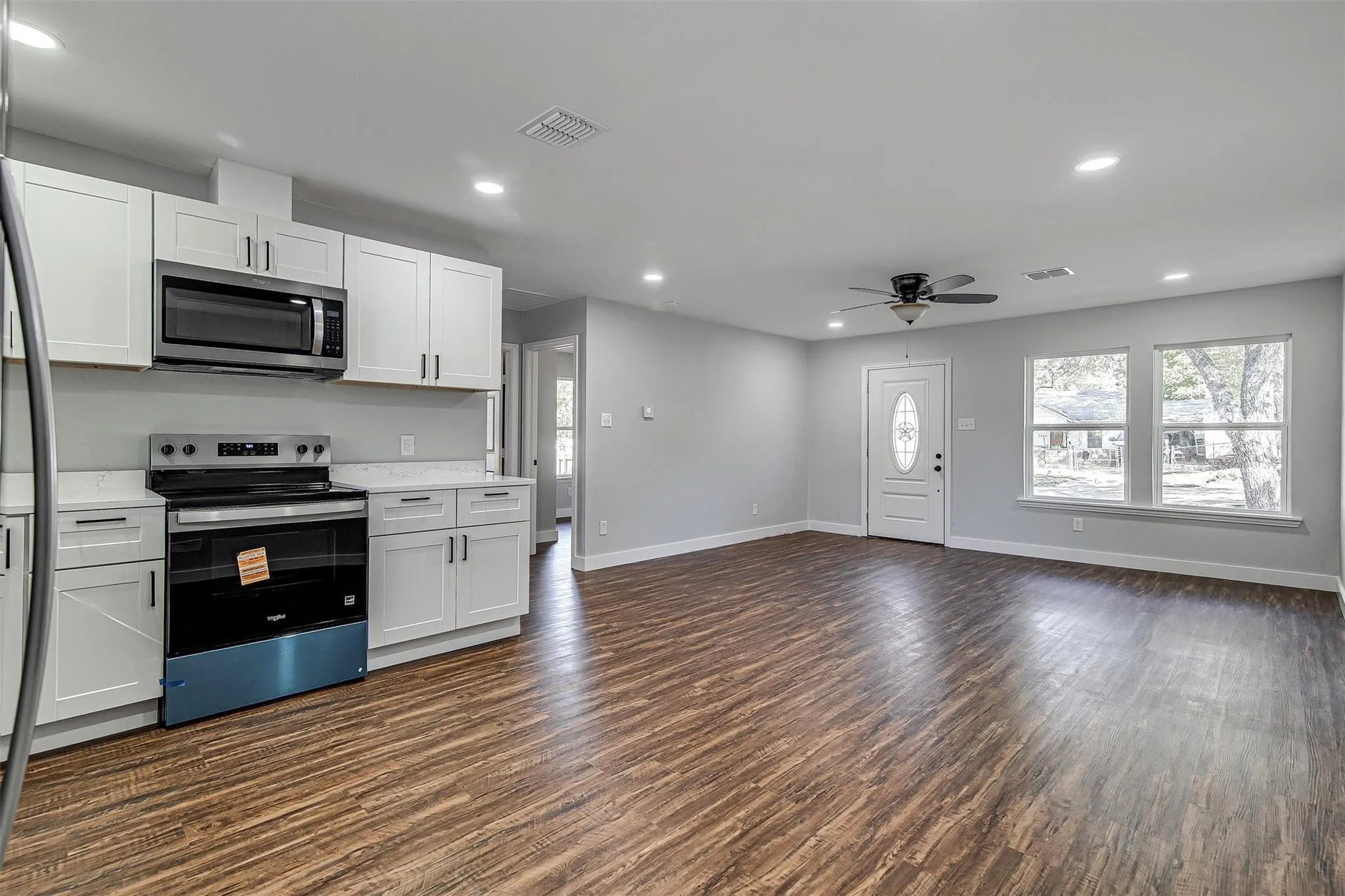 Open-concept living space with wood-finish flooring, recessed lighting, and a ceiling fan