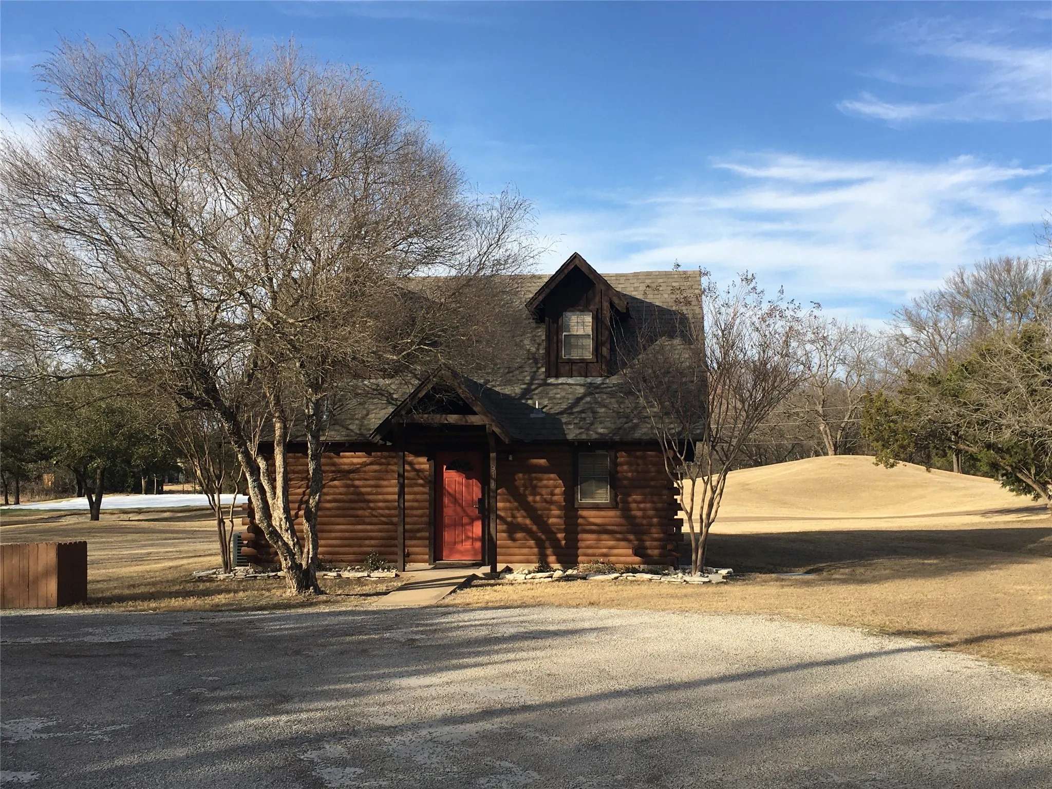 Log cabin exterior with dormer window, covered entry, and red door