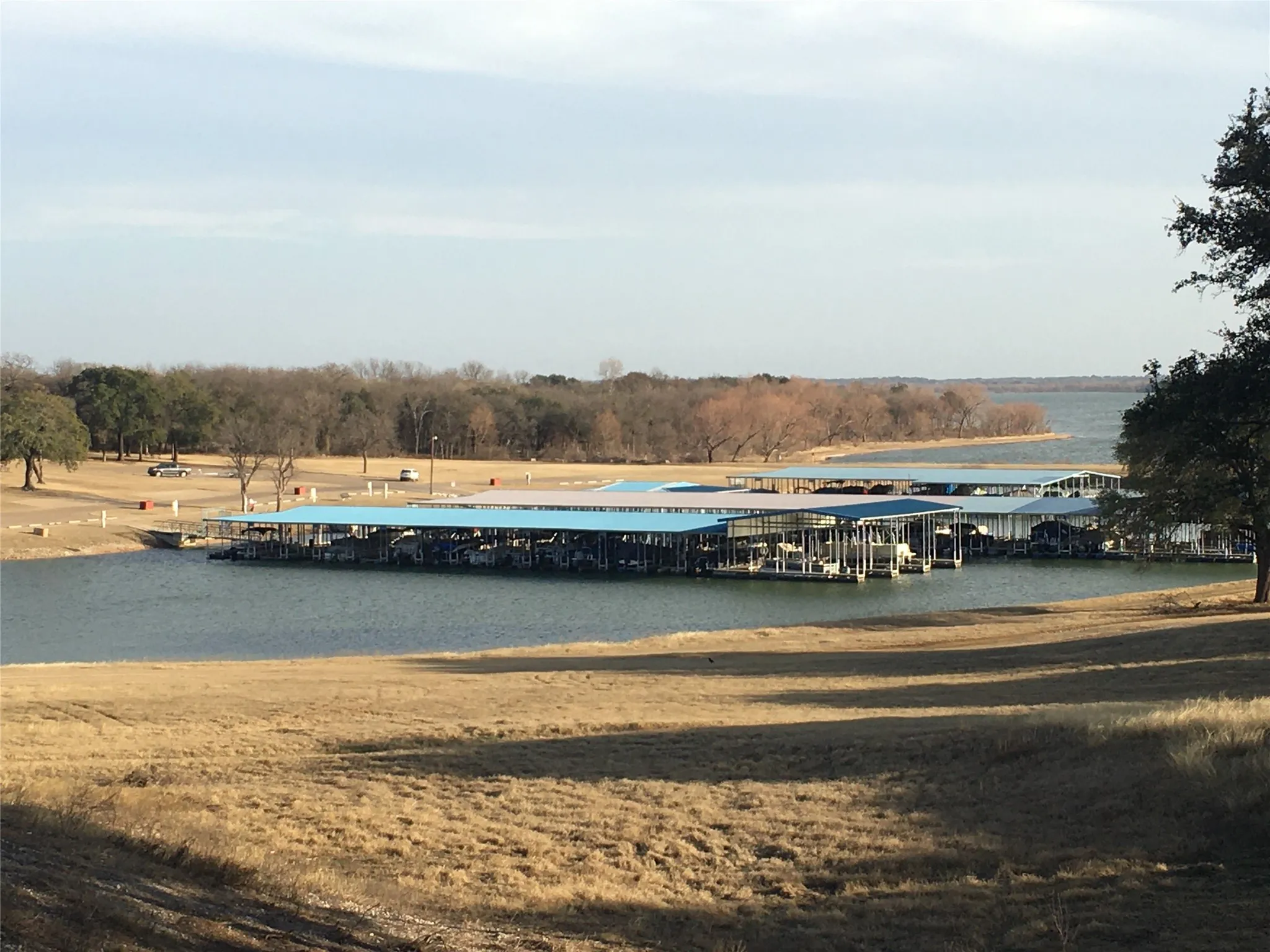 Waterfront setting with covered boat slips, expansive water frontage, and surrounding natural landscaping