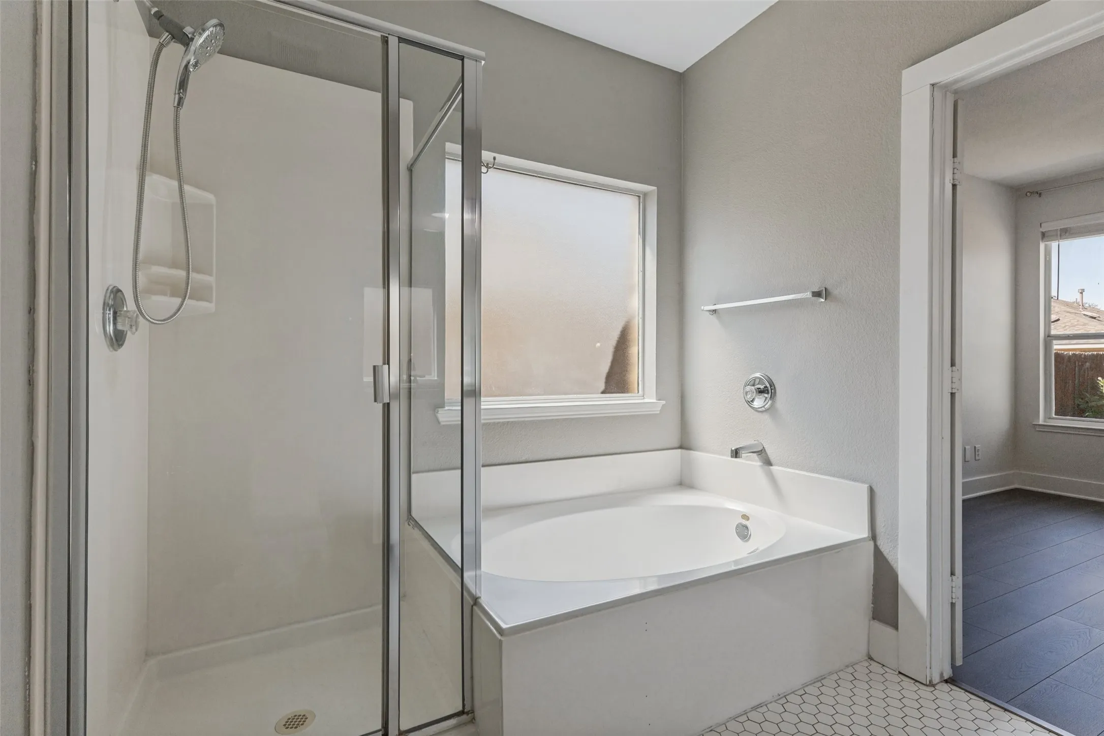 Walk-in shower with clear glass enclosure, built-in bathtub with white surround, hexagon tile flooring, and a window with privacy glass