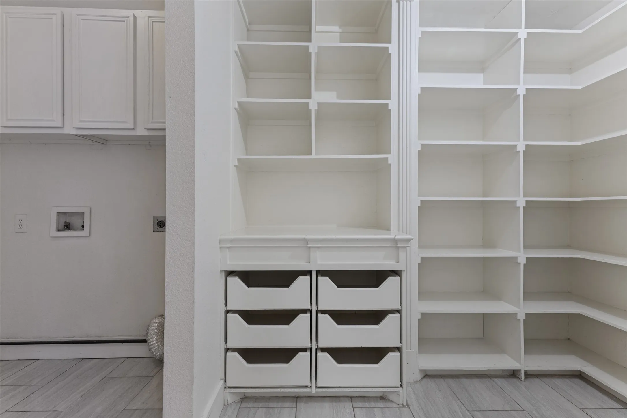 Expansive built-in shelving with multiple levels and corner units, featuring integrated drawers and overhead cabinetry