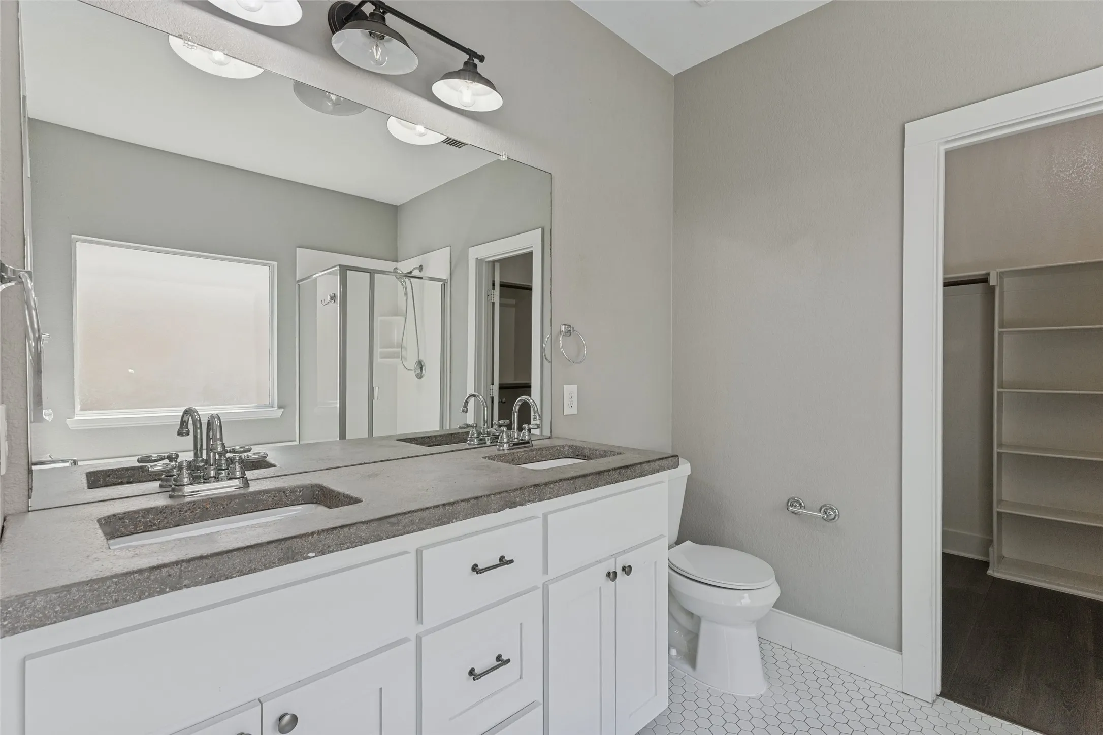 Double vanity with undermount sinks, white cabinetry, and dark countertop