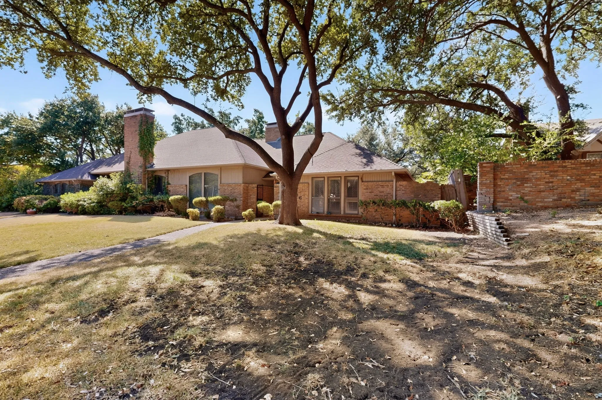 Brick exterior with a prominent chimney, mature trees, and a concrete​​‌​​​​‌​​‌‌​‌‌​​​‌‌​‌​‌​‌​​​‌​​ walkway